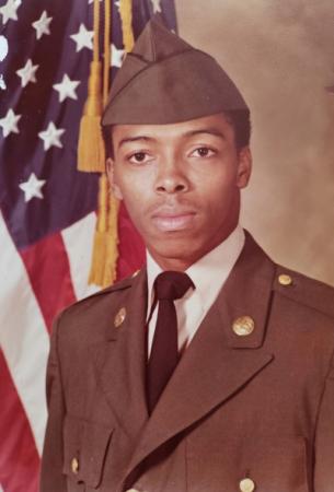 Young man in military uniform in front of american flag.